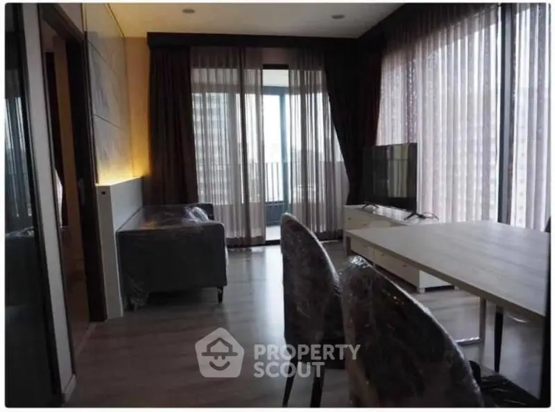Modern living room with large windows and stylish furniture in a high-rise apartment.
