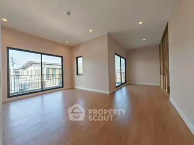 Spacious empty room with large windows and wooden flooring, ideal for customization.