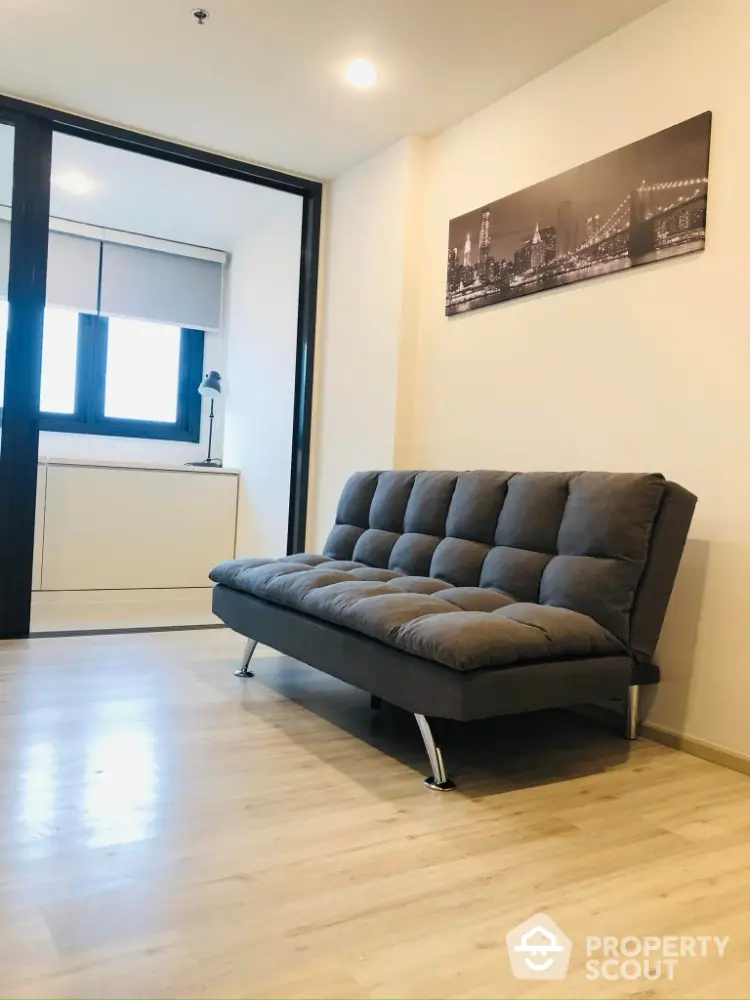 Modern living room with stylish gray sofa and cityscape artwork, featuring sleek wooden flooring.