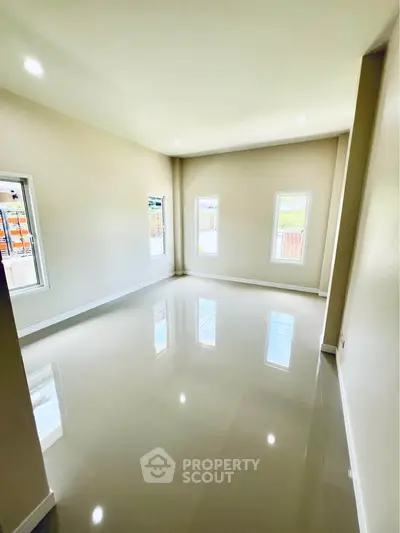 Spacious empty room with glossy floors and large windows, perfect for customization.