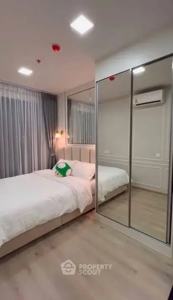 Modern bedroom with mirrored wardrobe and cozy lighting in stylish apartment.