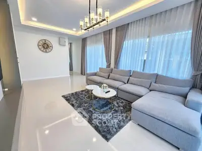 Luxurious modern living room with elegant chandelier and plush gray sofa.