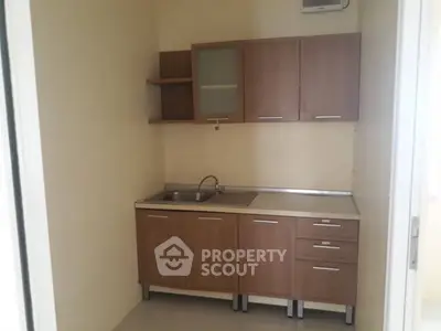 Compact kitchen with wooden cabinets and stainless steel sink in cozy apartment