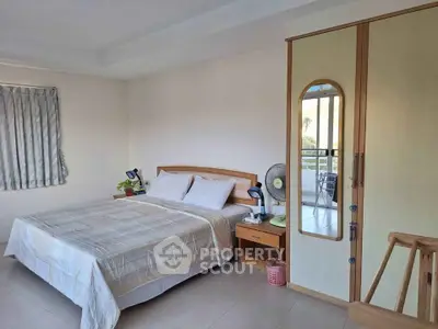 Spacious bedroom with ample natural light, featuring a large bed, wooden furniture, and access to a sunny balcony, ideal for a serene living experience.