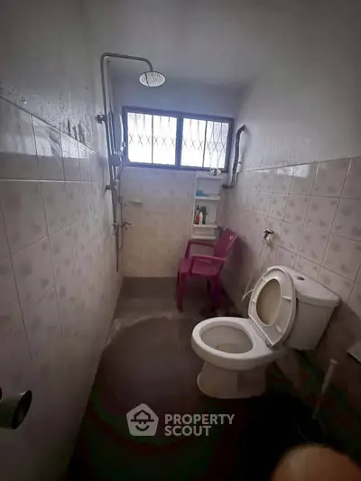 Compact bathroom with shower and toilet, featuring a window for natural light.