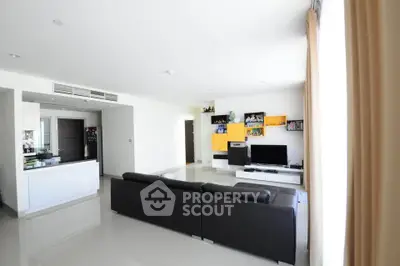 Spacious modern living room with sleek black sofa and stylish shelving, perfect for entertainment and relaxation.