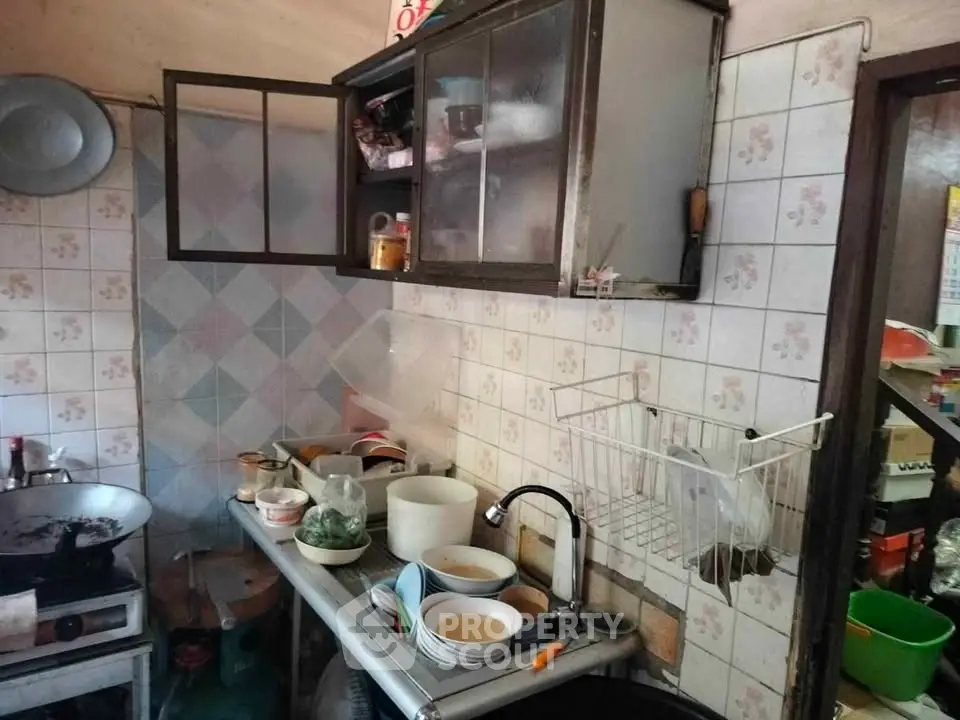 Cozy kitchen with vintage tiles and compact layout, featuring essential appliances and storage solutions.