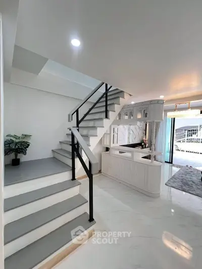 Modern interior with sleek staircase and open living area, featuring elegant design and natural light.