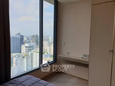 Modern bedroom with stunning city view from large window in high-rise apartment.
