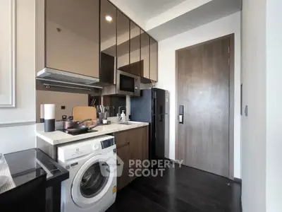 Modern kitchen with sleek cabinetry, washing machine, and built-in microwave in a compact layout.