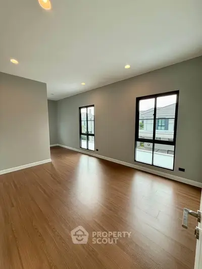 Spacious modern living room with large windows and wooden flooring in a contemporary home.