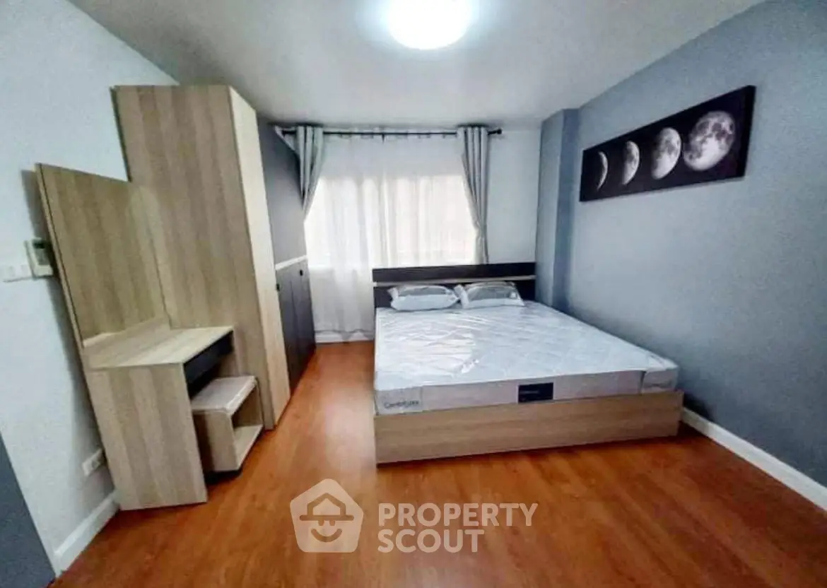 Modern bedroom with wooden flooring, stylish wardrobe, and moon phase artwork.