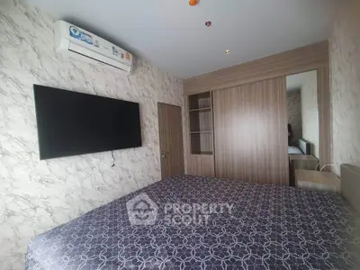 Modern bedroom with stylish decor, featuring a wall-mounted TV and air conditioning unit.