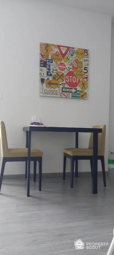 Modern dining area with stylish table and chairs, featuring unique wall art in a contemporary apartment.