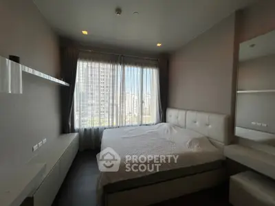 Modern bedroom with large window and city view, featuring a comfortable bed and sleek furnishings.