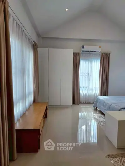 Spacious bedroom with large windows and modern furnishings, perfect for a serene living experience.