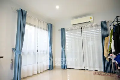 Bright and airy room with large windows and blue curtains, featuring a modern air conditioning unit.