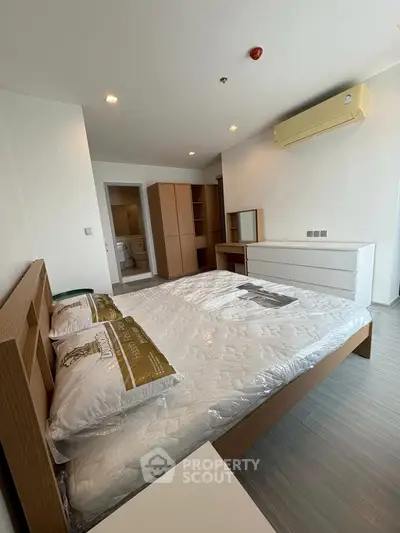 Spacious modern bedroom with sleek furniture and air conditioning in a stylish apartment.