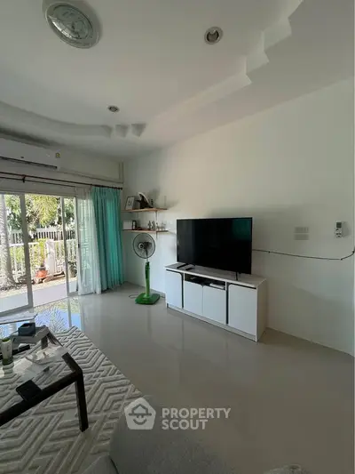 Modern living room with sleek TV setup and garden view through sliding glass doors.