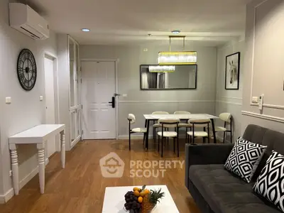 Stylish living room with modern decor and dining area, featuring elegant lighting and wooden flooring.