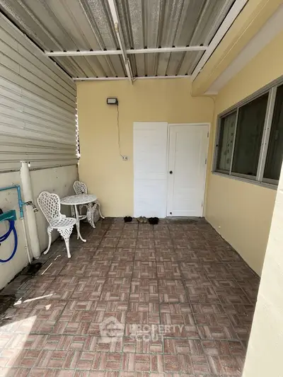 Charming covered patio with vintage furniture and tiled flooring, perfect for relaxation.