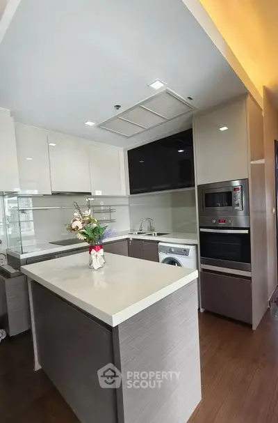 Modern kitchen with sleek cabinetry, island, and built-in appliances in a stylish apartment.