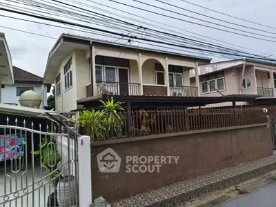 Charming two-story house with gated entrance and lush greenery in a serene neighborhood.