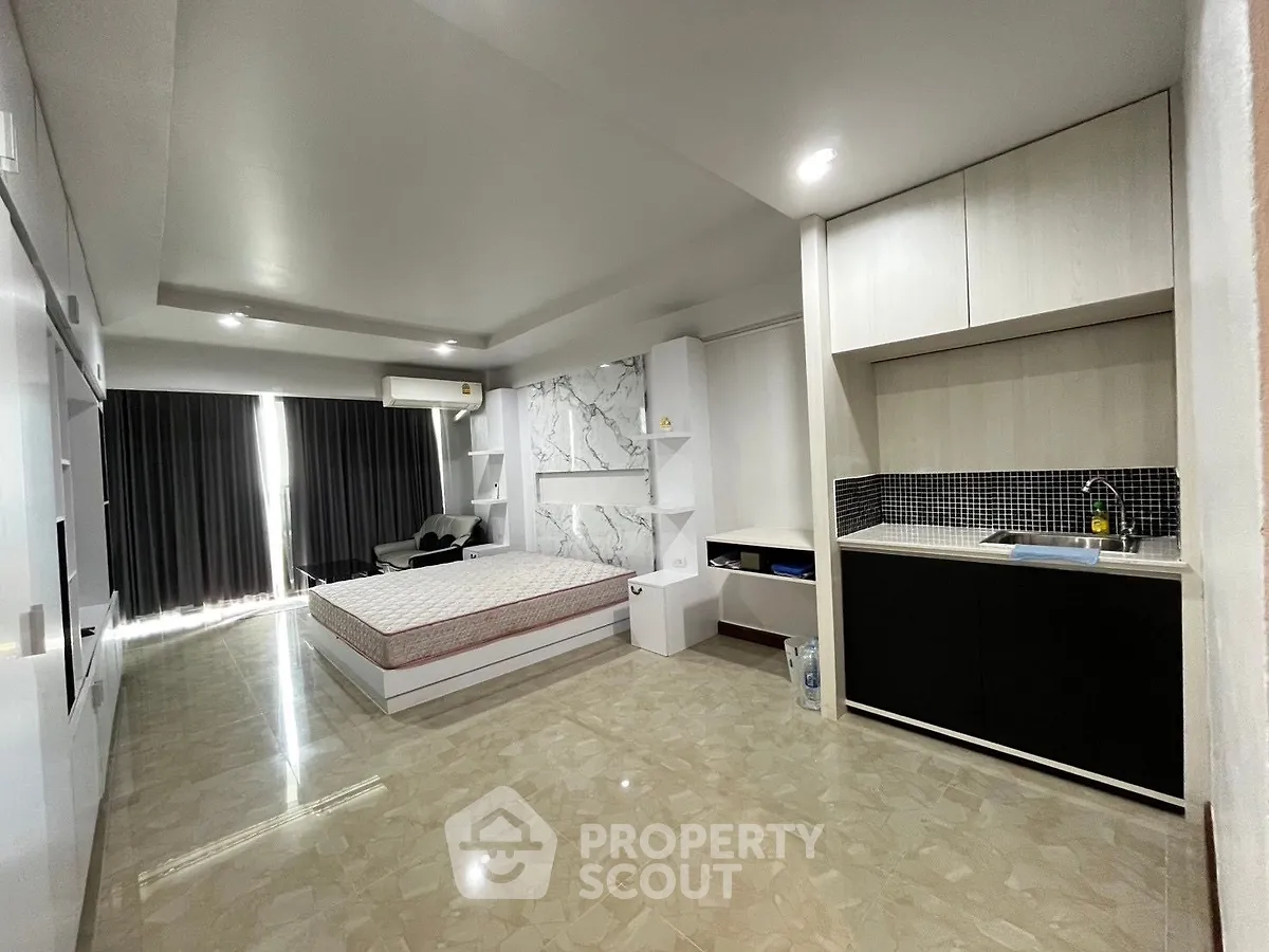 Spacious modern studio apartment with sleek kitchen and cozy sleeping area, perfect for urban living.