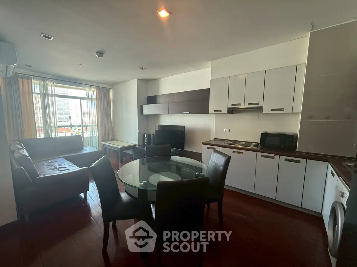 Modern open-layout living room with kitchen, featuring sleek furniture and city view.