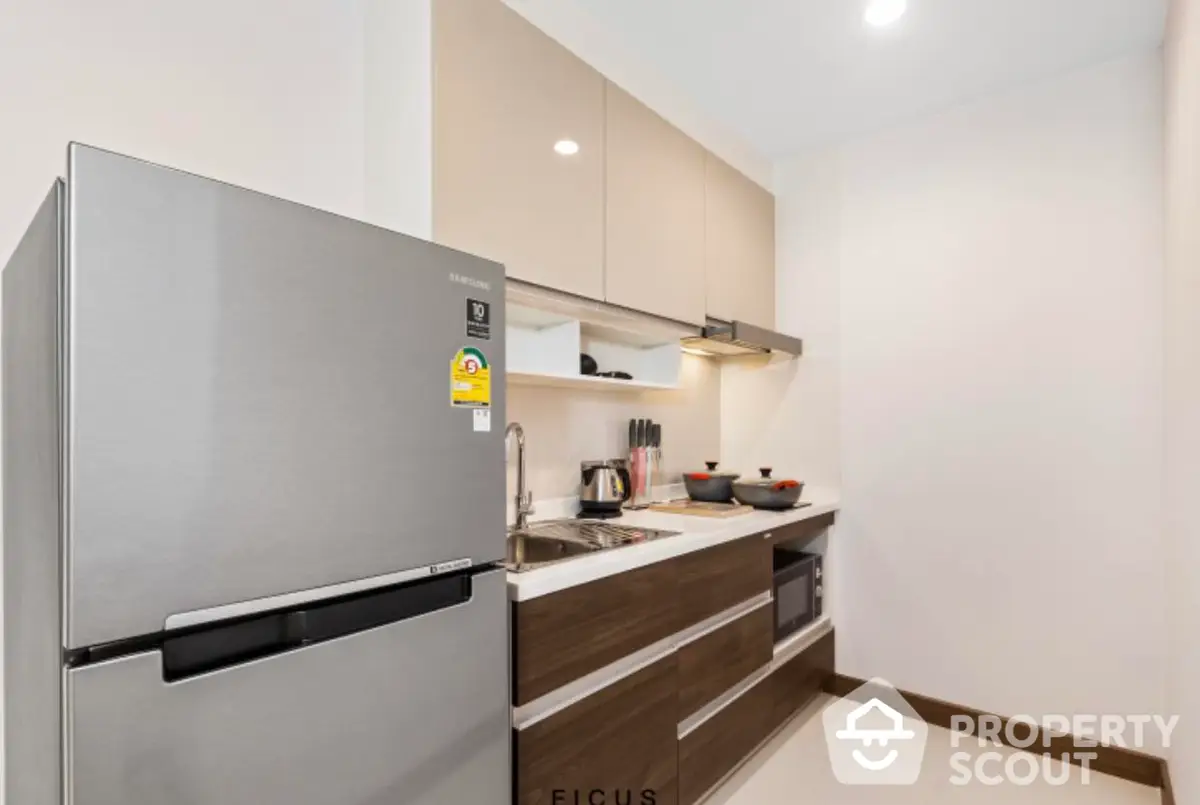 Sleek modern kitchen with stainless steel fridge, built-in oven, and ample cabinet space, perfect for culinary enthusiasts.