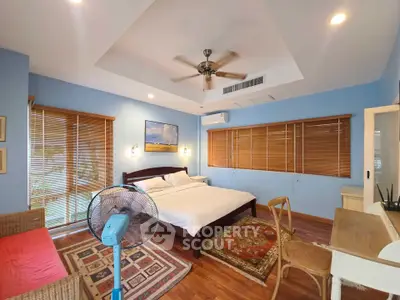 Spacious bedroom with wooden flooring, cozy decor, and ample natural light.