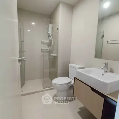 Modern bathroom with sleek fixtures and glass shower enclosure in a contemporary apartment.