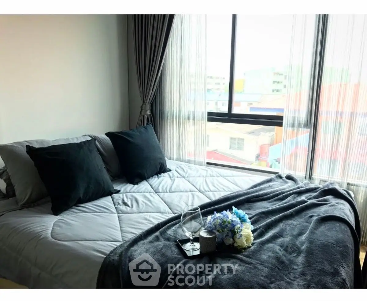 Cozy bedroom with large window and stylish decor in modern apartment.