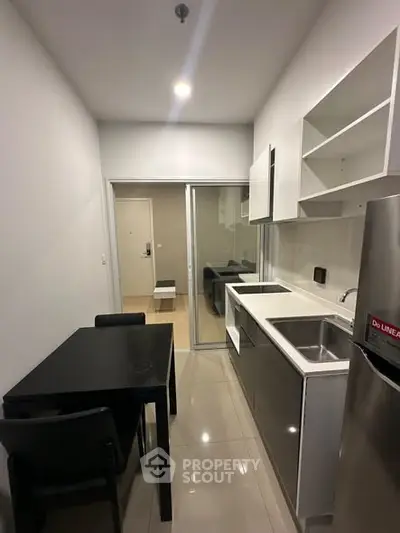 Modern kitchen with sleek design, featuring stainless steel appliances and a compact dining area.