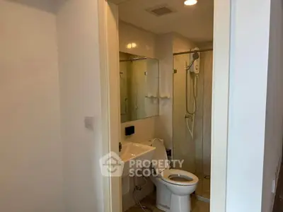 Compact bathroom with modern fixtures and glass shower enclosure in a cozy apartment.