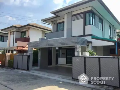 Modern two-story house with sleek design and spacious driveway in suburban neighborhood.