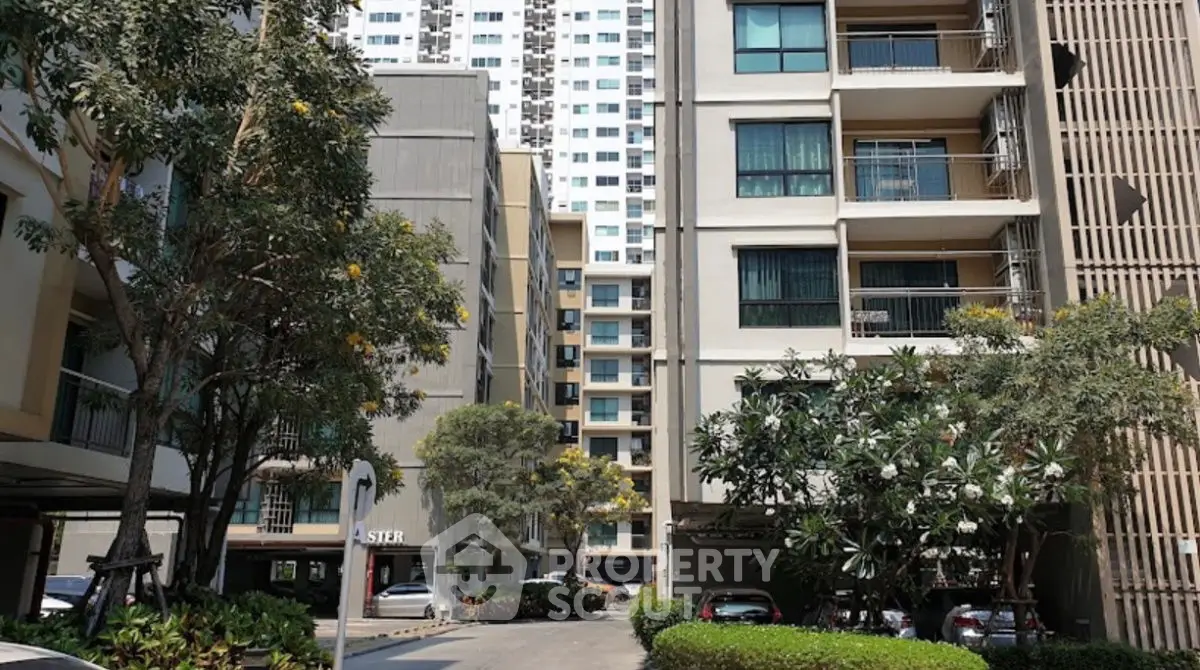 Modern apartment complex with lush greenery and ample parking space.