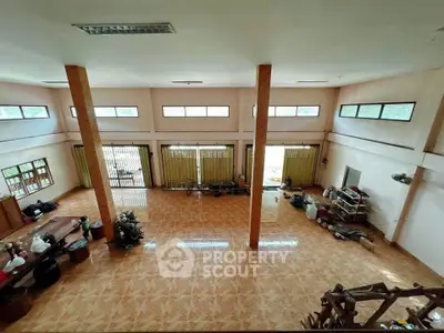Spacious open-plan living area with high ceilings and large windows, perfect for natural light and versatile use.