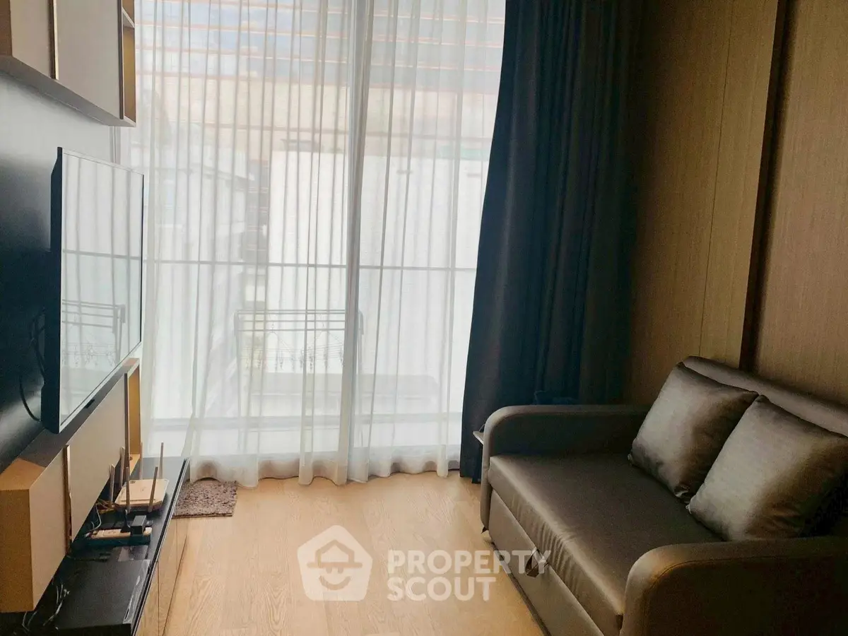 Cozy living room with modern TV setup and plush sofa near large window.