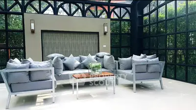 Luxurious sunroom with modern seating and large windows offering garden views.