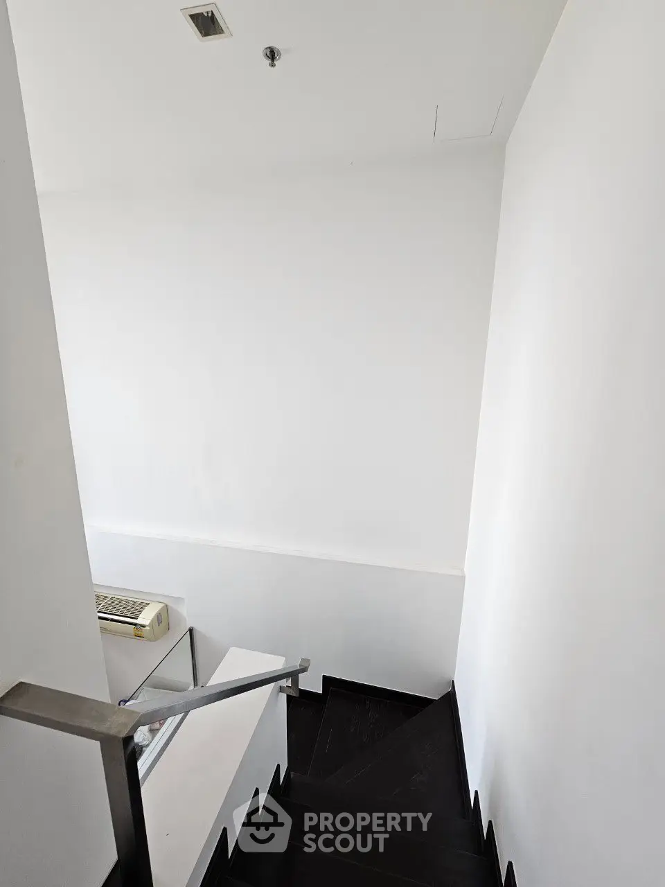 Modern staircase with sleek black steps and minimalist white walls in a contemporary building.