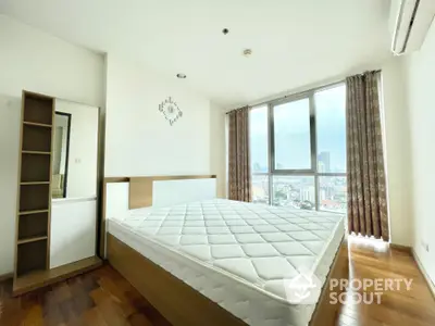 Spacious bedroom with large window offering stunning city views and modern furnishings.