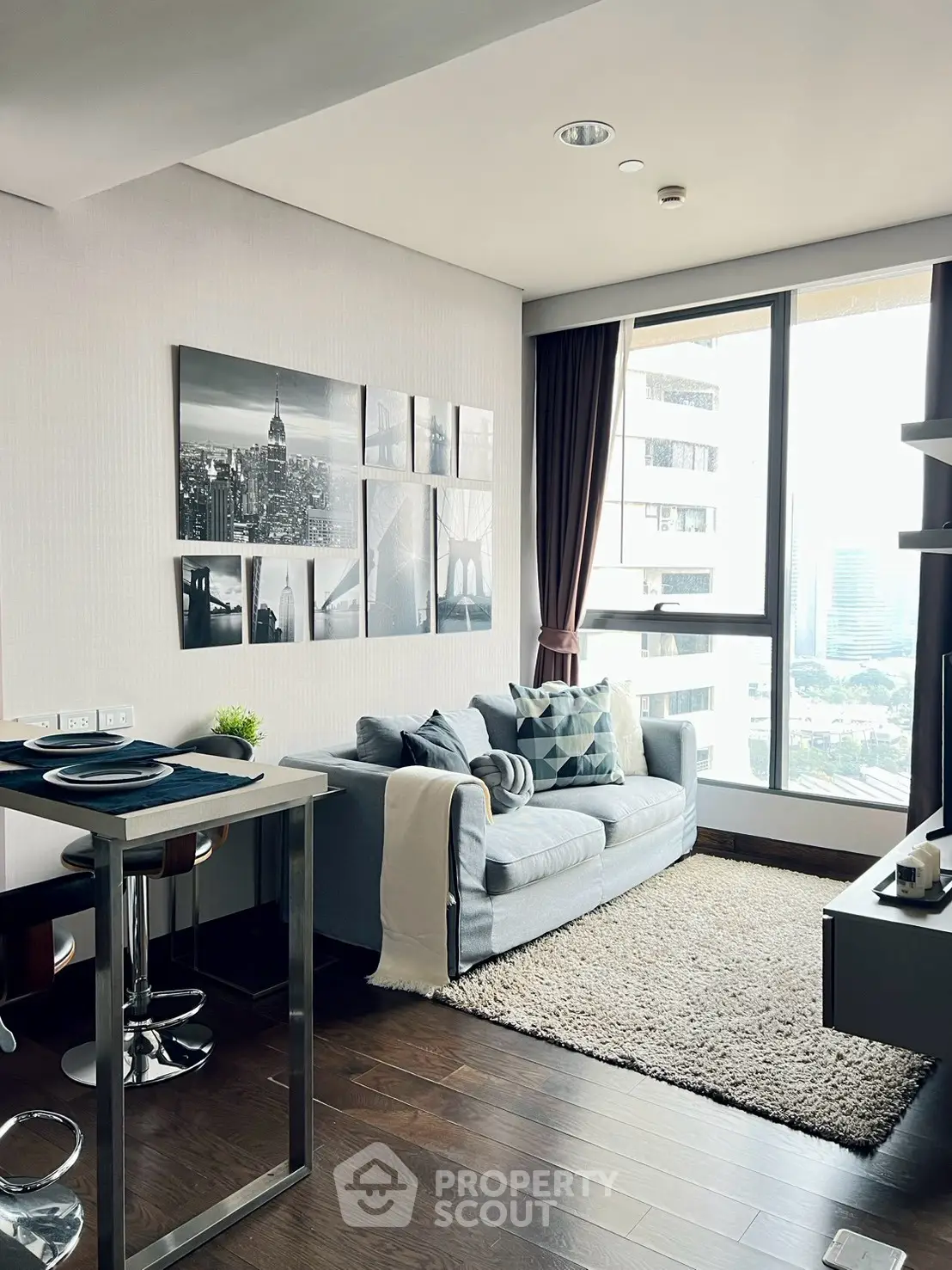 Modern living room with city view, stylish decor, and cozy seating area in a high-rise apartment.