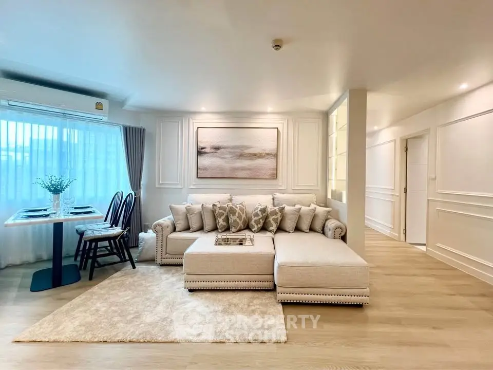 Elegant living room with plush sectional sofa and dining area, featuring modern decor and natural light.