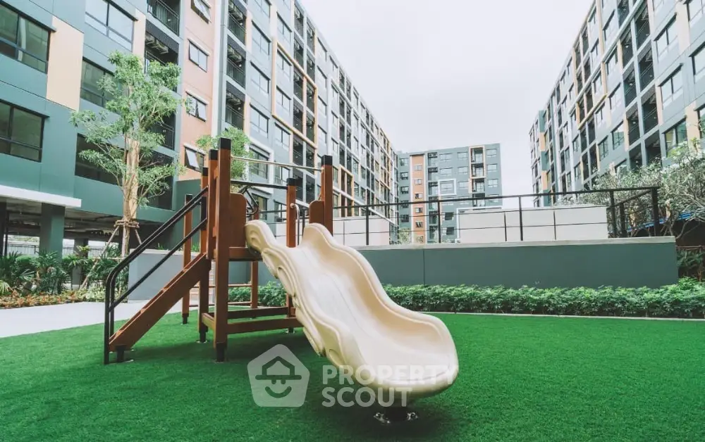 Modern apartment complex with playground slide and lush green lawn