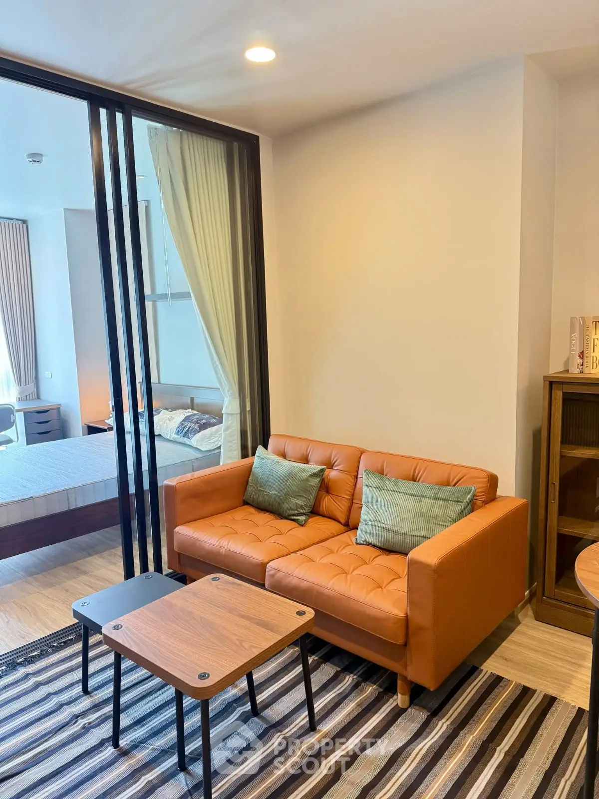 Modern living room with stylish orange sofa and view into cozy bedroom