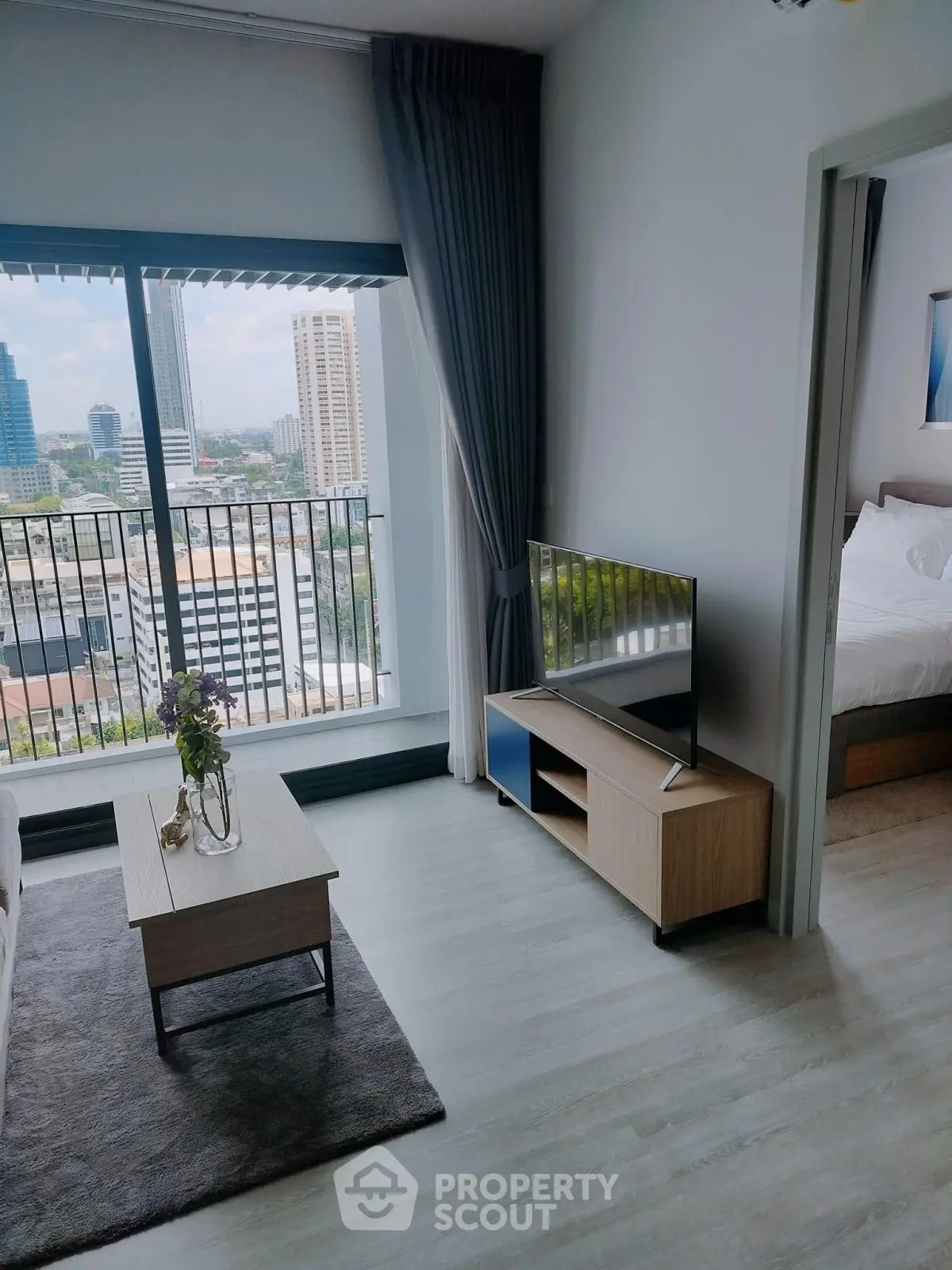 Modern living room with city view, featuring sleek furniture and large windows for natural light.