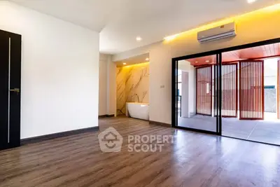 Spacious modern living area with wooden flooring and large windows.