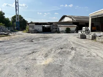 Expansive industrial property with open yard and storage buildings under clear blue sky.