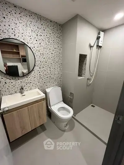 Modern bathroom with terrazzo wall, round mirror, and walk-in shower